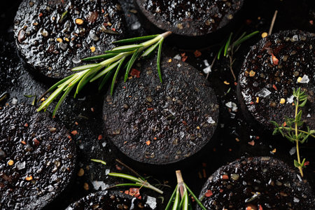 Black pudding or blood sausage with rosemary on a iron cast panの写真素材
