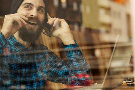 Young hipster man working on laptop in coffee shopの写真素材