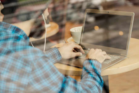 Young hipster man working on laptop in coffee shopの写真素材