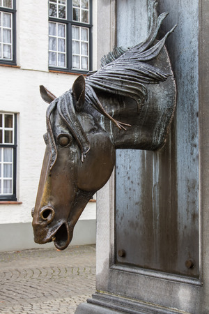 A horse head is made of metal attached to a fountain.の写真素材