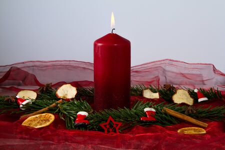 burning red candle with fir branchesの写真素材