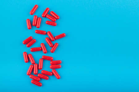 Red pills (capsules) on blue background with copy space for textの写真素材