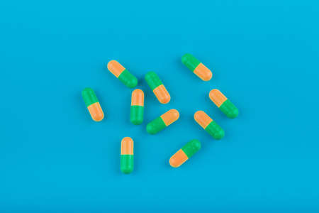 Yellow-green pills (capsules) on a blue background, top viewの写真素材