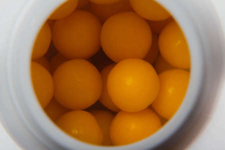 round orange vitamin close up inside a white bottle, medical concept, top view, close-up.の写真素材