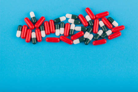 A heap of mixed colored pills on a blue background with copy space for text