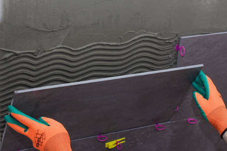 construction worker installing wall tile at home repair renovation work close upの写真素材