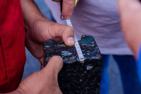 Road workers take a cube of asphalt to verify