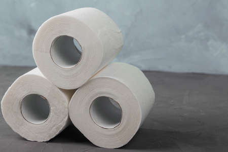 Pyramid of three toilet paper rolls on a gray background, close-upの写真素材