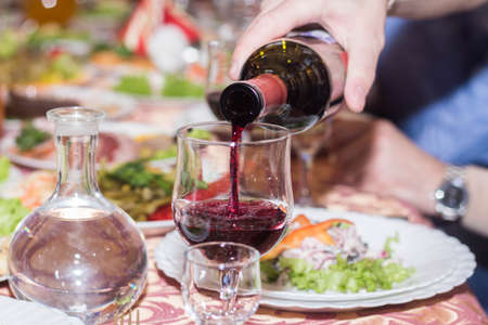 The waiter pours red wine poured into a glassの写真素材