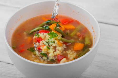 Vegetable soup in a ceramic bowl is mixed with a spoon. Vegetable foodの写真素材