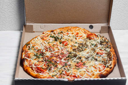 Pizza in a cardboard box on a white wooden background. View from above. Pizza delivery. Pizza menu.の写真素材