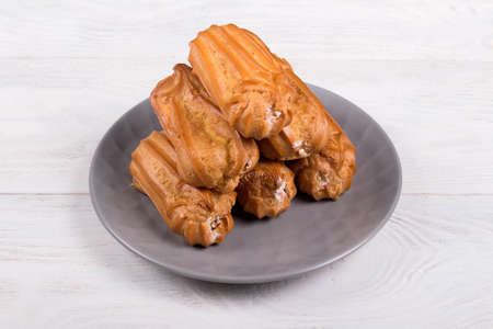 Profiteroles with custard, dessert on gray plate, on white wooden background