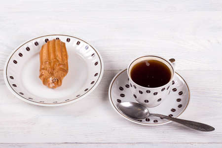 Profiteroles with cream on the table with a Cup of coffee, white wooden backgroundの写真素材