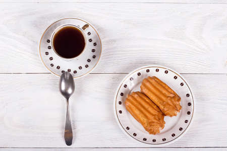 Profiteroles with cream on the table with a Cup of coffee, white wooden backgroundの写真素材
