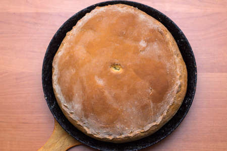 Kurnik, Russian meat pie. A traditional dish of dough lies in a black pan on the table. Meat pie....