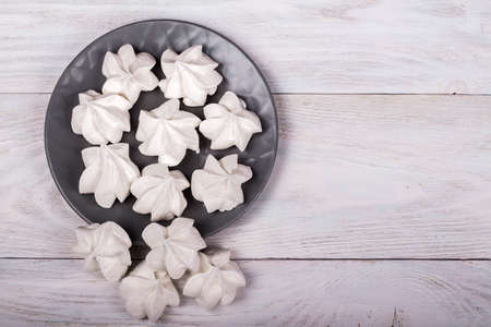 merengues on gray plate on white wooden background, sweet and tastyの写真素材
