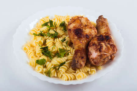 Grilled chicken drumstick and pasta on white plate, white background, close upの写真素材
