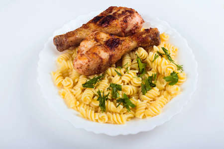 Grilled chicken drumstick and pasta on white plate, white background, close upの写真素材
