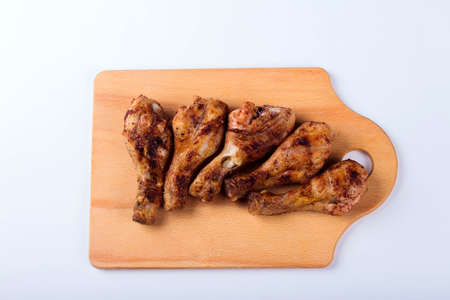 Grilled chicken shins on a wooden tray, white background