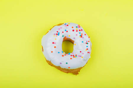 Donut with pink glaze on a yellow background, close-up