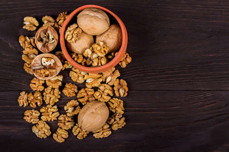 whole walnuts and kernels on wooden background, healthy brain food, walnut on a dark old table in a...