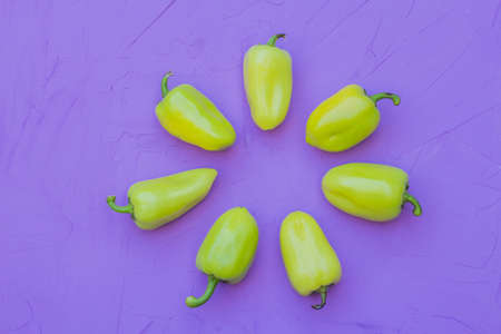 some green bell peppers on lilac background, top view