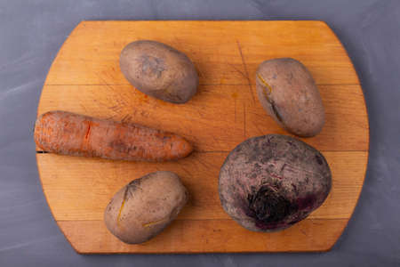 Boiled vegetables lie on a wooden tray on a gray backgroundの写真素材