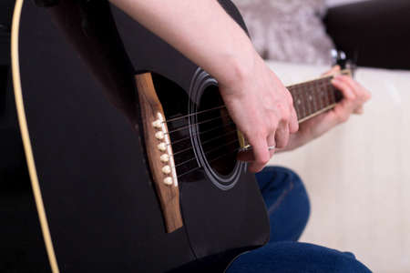 woman's hands playing acoustic guitar, close up