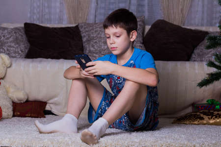 children, technology, internet communication and people concept - boy with smartphone texting...