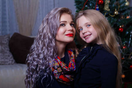 happy mother and daughter, posing against the Christmas tree, Christmas and new year mood, close-up.