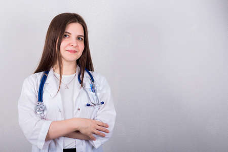 female doctor or nurse standing with stethoscope, medicine concept, gray backgroundの写真素材