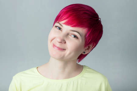 Portrait of a beautiful happy smiling woman with short dark pink hair