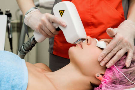 A woman in a beauty salon takes a procedure for laser depilation of the upper lip with a cosmetologistの写真素材