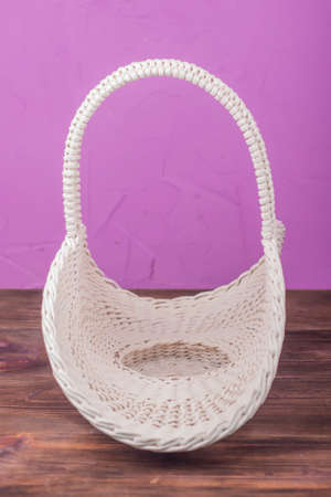 Beautiful white vintage wicker basket on a wooden table. An empty wicker basket made of paper tubesの写真素材