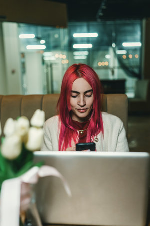 A girl with red hair is sitting with a laptop in a cafeの写真素材