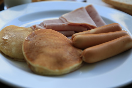 Breakfast of pancakes, ham, toast and sausages with lemonade and coffeeの写真素材