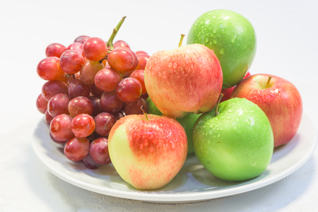 Apple and grape fruit on dishの写真素材