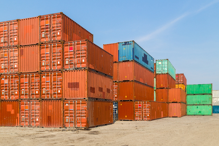 Stacked color cargo containers over the blue sky with clouds