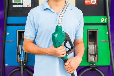Man hold fuel nozzle to add fuel in car at gas station.