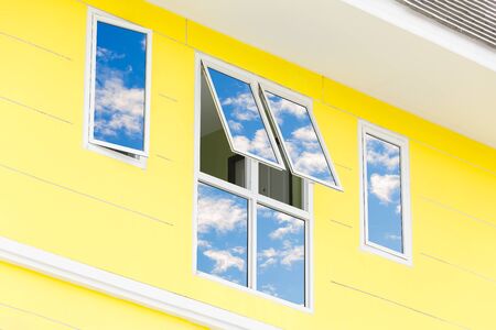Blue sky with clouds reflected in glass windows of modern office building.の写真素材