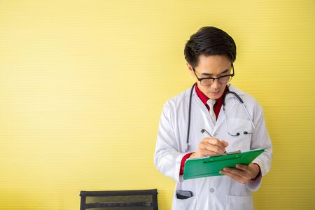 Senior doctor reading and writing patient profile.の写真素材