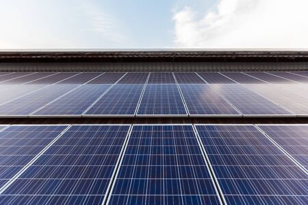 Solar Panel Photovoltaic installation on a Roof of factory, sunny blue sky background, alternative electricity source - Sustainable Resources Concept.の写真素材