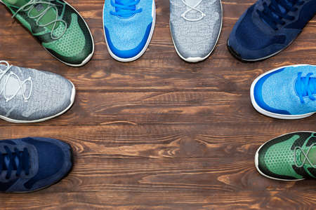 Top view shop display of unbranded modern new stylish sneakers running shoes for men on wooden background texture with copy space.のeditorial素材