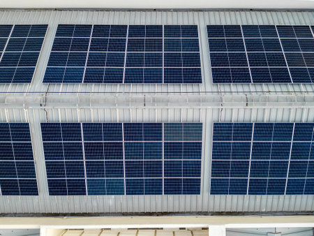 Aerial top view of blue solar photo voltaic panels system on the large industrial factory building roof top or a warehouse. Renewable ecological green energy production concept.の写真素材