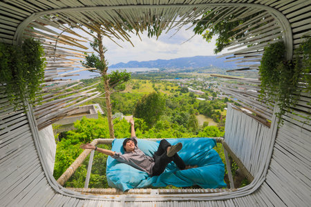 Man lying down on sofa bed  Man is lying down on sofa bed near terrace in cafe outdoor with scenic...