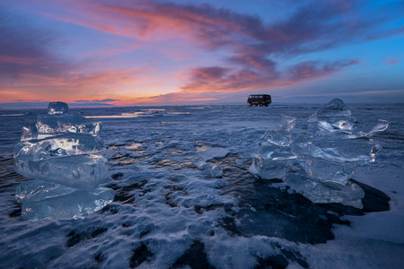 Sunset reflected in a large block of ice hummock on the frozen lake background.の写真素材