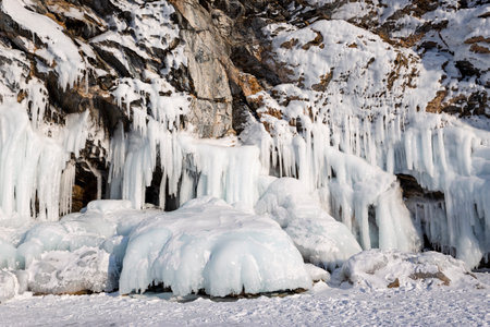 Baikal Lake in the winter cold day. Beautiful icy rocks with big ice crust.long icicles on the icy coastal cliffs of Olkhon Islandの写真素材