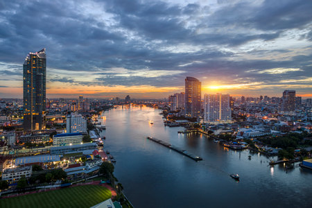 Modern buildings in the city with water reflection, river ferry boat at twilight time.