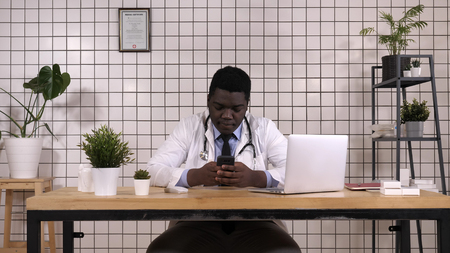 African American Doctor Holding Smart Phone Texting.の写真素材