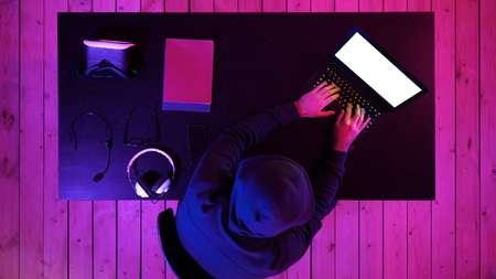 Cybercrime, hacking and technology concept - male hacker in dark room writing code or using computer virus program for cyber attack. White Display.の写真素材